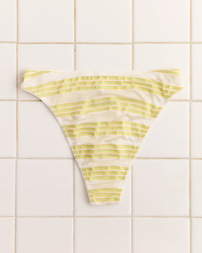 Apple Briefs bikini bottoms in yellow and white stripes, designed in a high-cut brief style, are displayed on a white tiled surface.