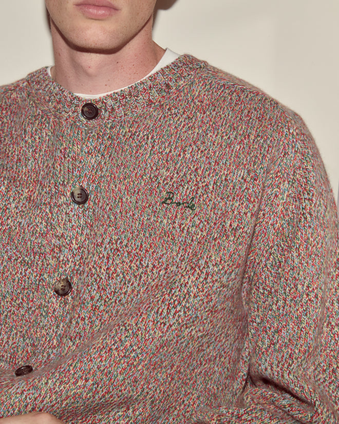 A person wearing the Atlas Cardigan—a boxy, multicolored knit with large buttons and hand-embroidered Bode text on the chest.