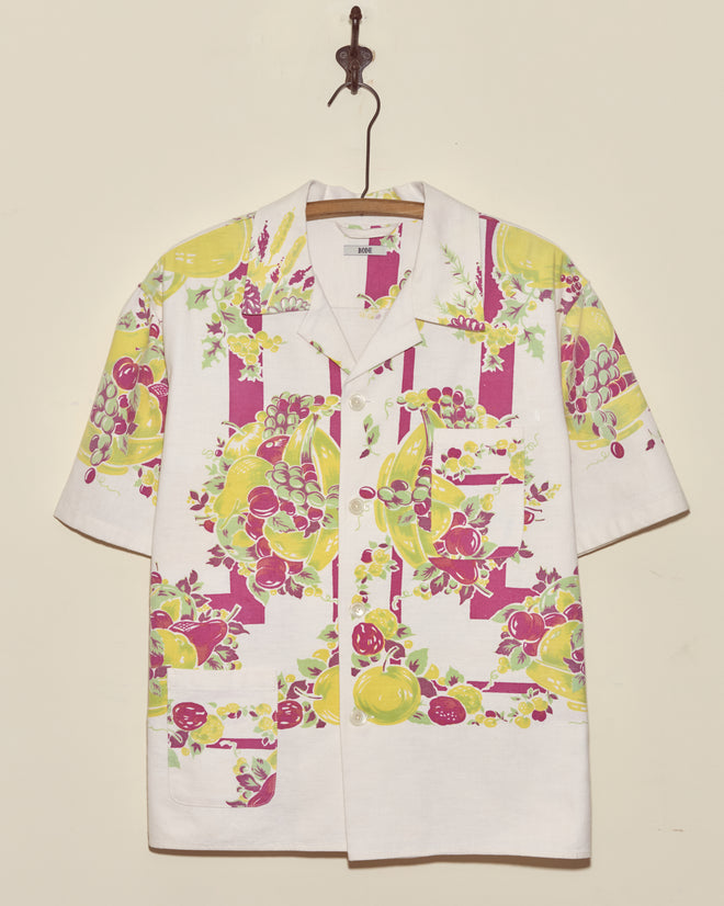 Banana Bunch Short Sleeve Shirt - L/XL: White short-sleeve shirt with a vibrant banana-themed pattern, inspired by vintage tablecloths, displayed on a hanger.
