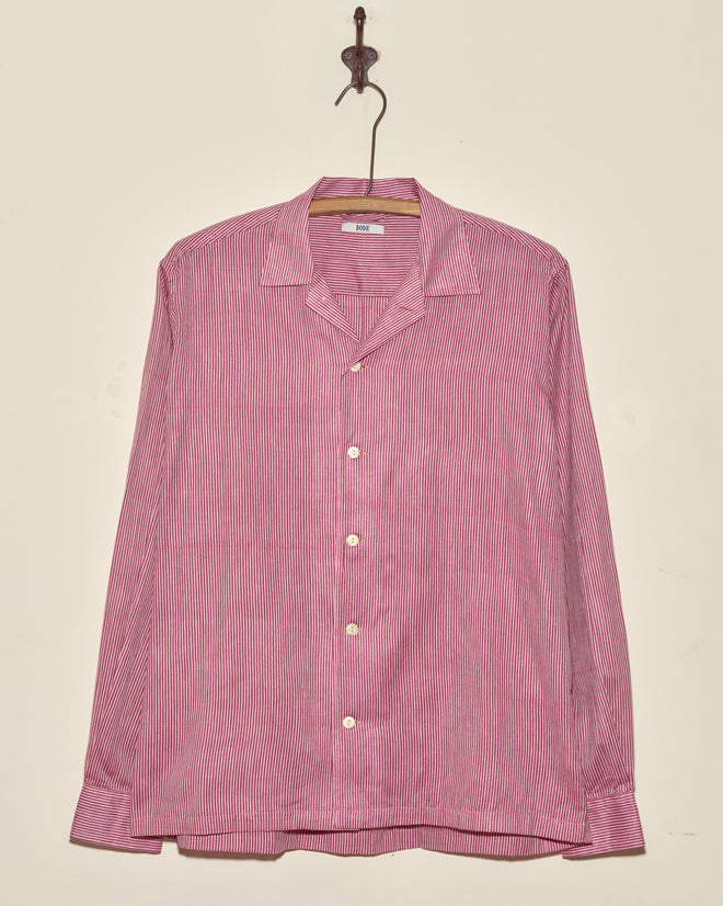 A Berry Creme Stripe Shirt in size S/M with vintage red and white stripes and long sleeves hangs on a hook against a plain wall.