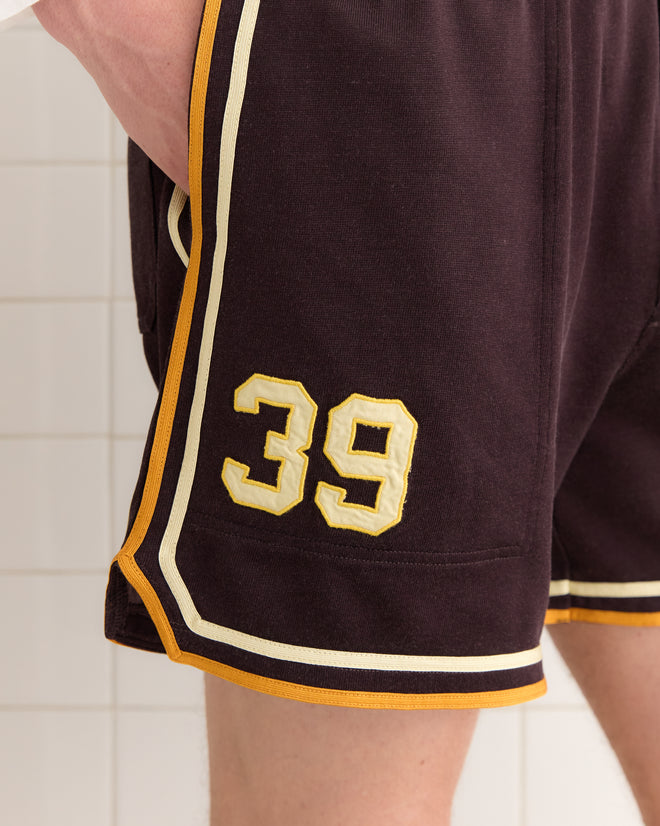 Close-up of Bobcat Shorts, designed with vintage flair. Dark fabric is accented by yellow and white trim, featuring the number 39 on the side—a stylish homage to 1970s reproduction aesthetics.