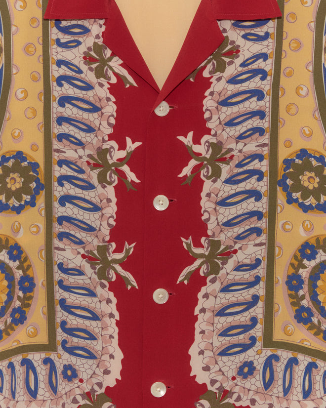 Close-up of the Bricolage Long Sleeve Shirt, a 1960s-inspired silk shirt with red, yellow, blue, and white floral and geometric patterns, finished with white buttons.