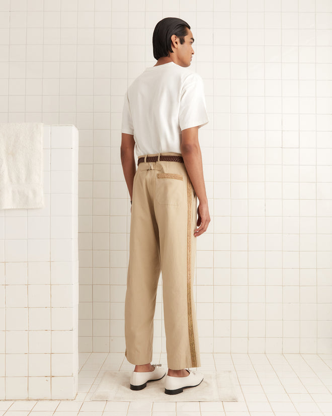 The person in a white Sportsman Patch Pocket Tee, made of 100% cotton, and beige pants stands in a tiled room, facing away.
