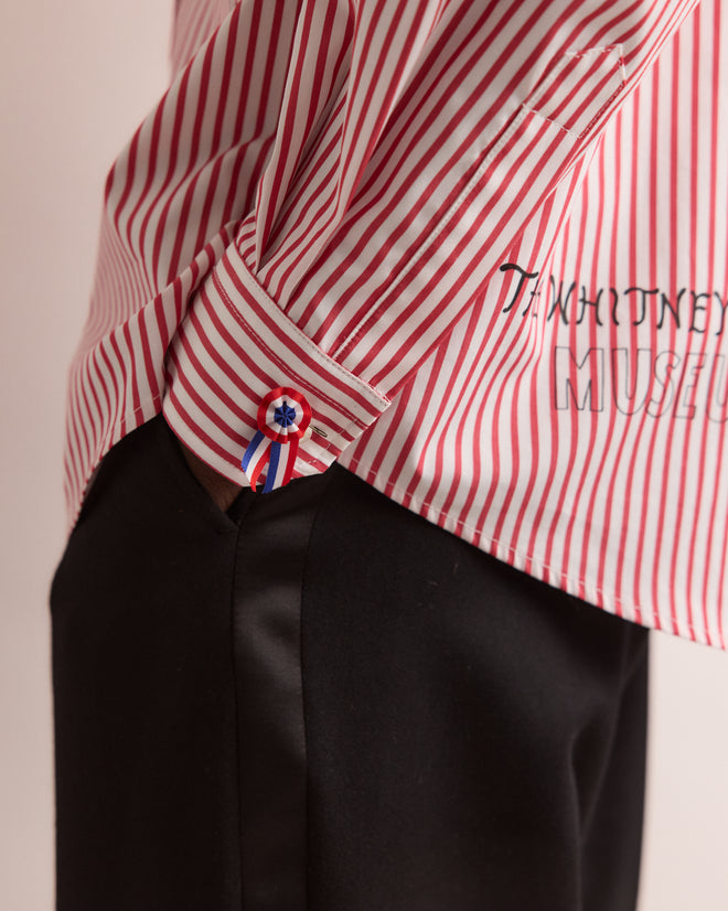 Wearing the Calder Painted Cirque Long Sleeve Shirt in red and white stripes with a ribbon cuff, this person pairs it with black pants and keeps one hand in their pocket.