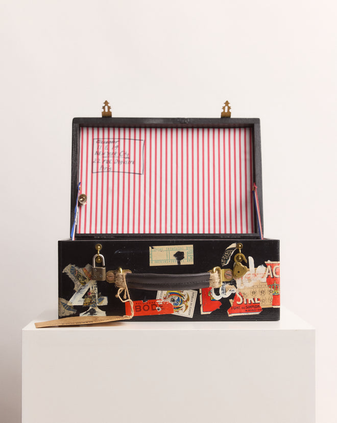 The Calder Suitcase Box—a vintage-inspired case with travel stickers and a red-and-white striped interior—captures the playful spirit of Calder’s Circus, reminiscent of the Whitney Museum of American Art.
