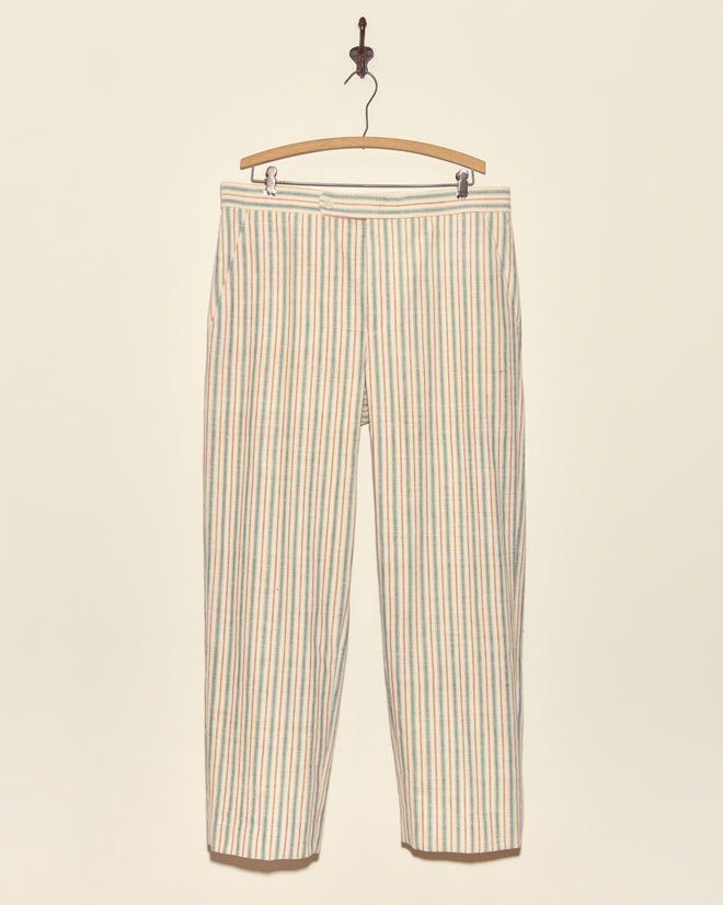 Chart Stripe Trousers - 36: Beige handwoven trousers with vertical pastel blue, pink, and green stripes, crafted from vintage Chinese fabric, displayed on a wooden hanger against a wall.