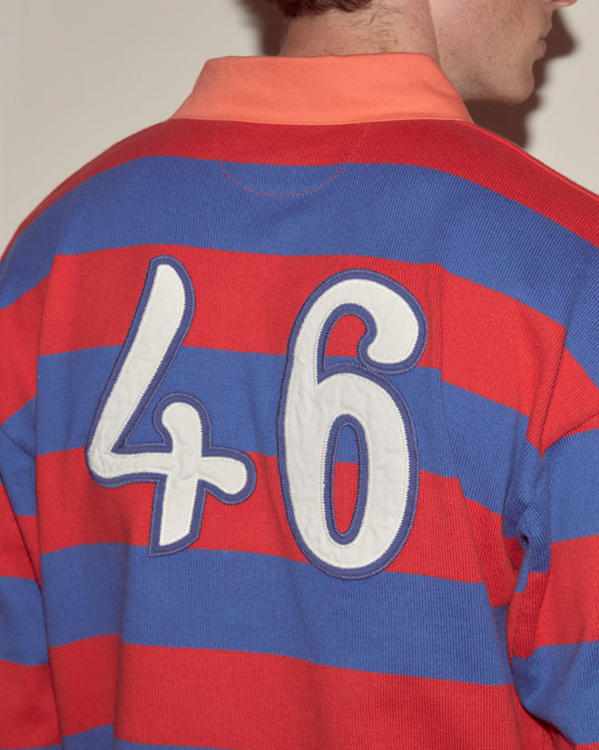 Wearing the Clubhouse Rugby Shirt, featuring bold red and blue stripes, crafted from 100% cotton with a large white