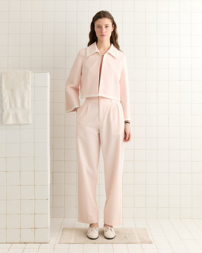 A woman in a Club Stripe Swing Jacket stands in a tiled room, with a towel draped nearby.