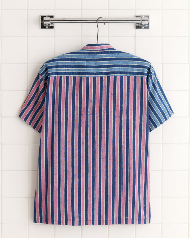 Cobalt Coral Stripe Shirt - L/XL: short-sleeve, vertical blue and pink stripes, made from deadstock fabric. Displayed on a hanger against a white tiled wall.