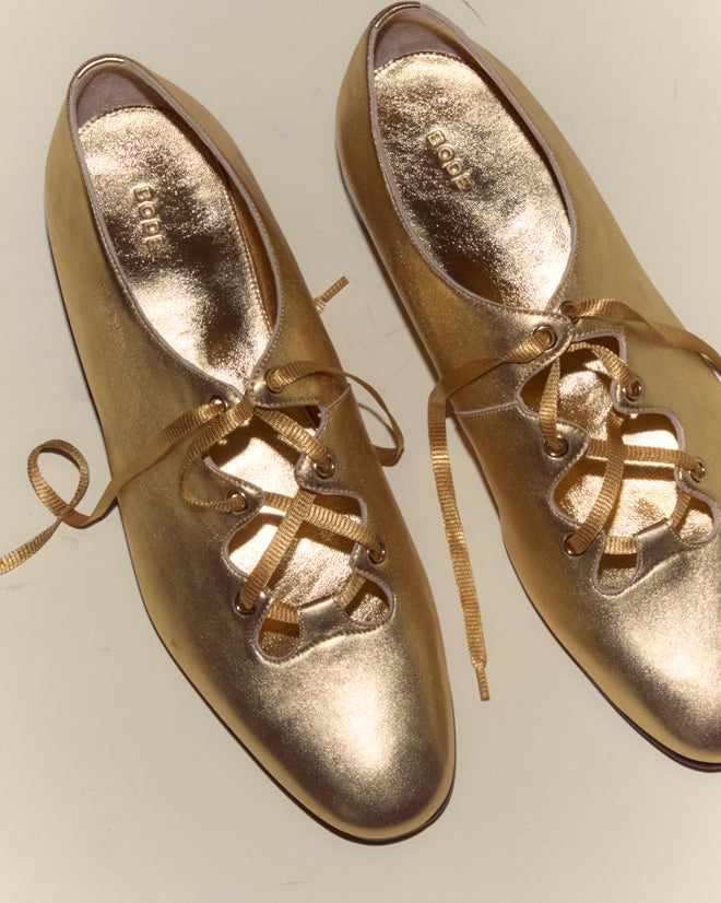 The County Clare Shoes - Metallic are shiny gold lace-up shoes made from metallic-treated leather with ribbon laces, shown from above on a light background.