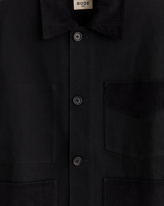 Close-up of the Craft Jacket - Black, a heavyweight cotton twill button-up with corduroy collar and pockets, featuring a