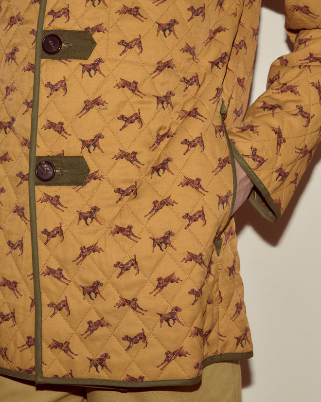 Close-up of the Crittendon Liner Coat in mustard, featuring a playful dog motif, dark buttons, a cozy knit collar, and hand in pocket.