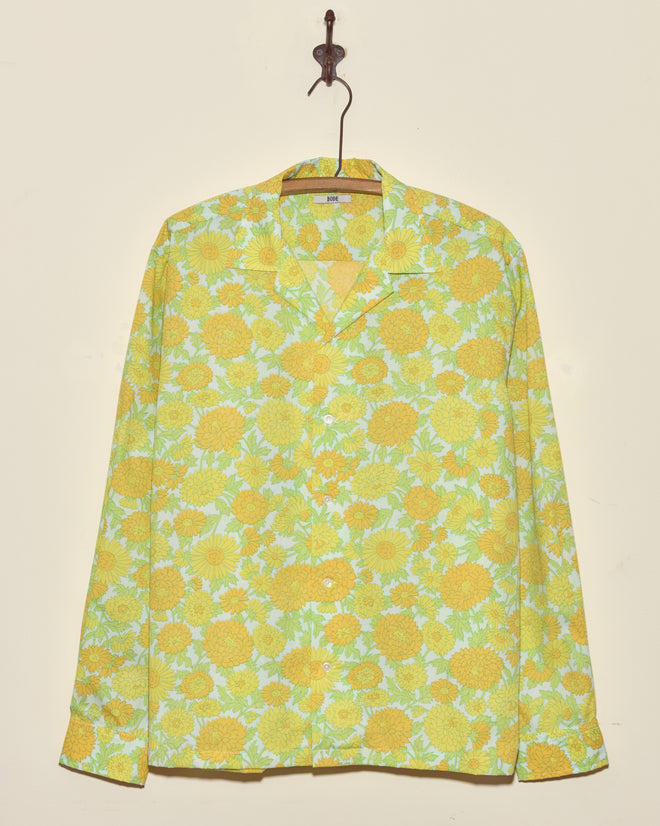 Dhalia Lime Long Sleeve Shirt (XL/XXL) with yellow and green floral pattern, button-up style, hangs on a hook against a beige wall.