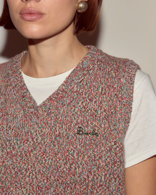Woman wearing the Falls Vest - Multi, a women’s knitwear V-neck sweater vest, layered over a white shirt with gold earrings and short brown hair.
