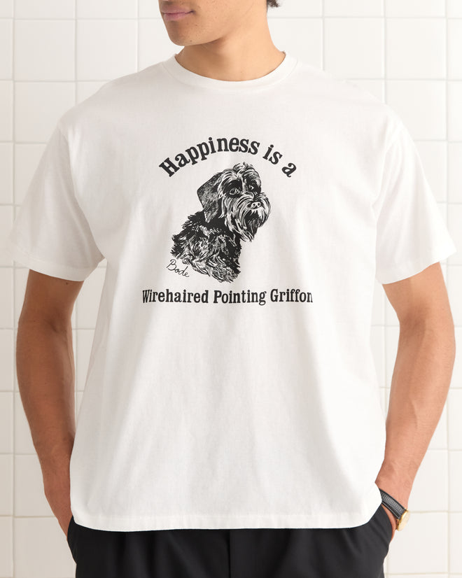 A man wears the Happiness Tee, a 100% cotton white T-shirt featuring a dog illustration and the text: