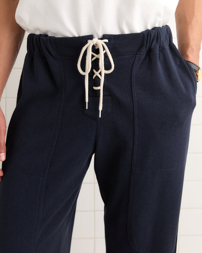 Close-up of a person wearing Lace-Front Sweatpants in navy blue with white lace-up detail at the waist, paired with a white shirt.