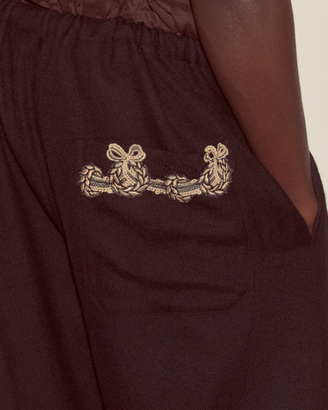 Close-up of the Laurelist Pajama Pants in black, showing a pocket with intricate beige knot embroidery inspired by vintage passementerie.