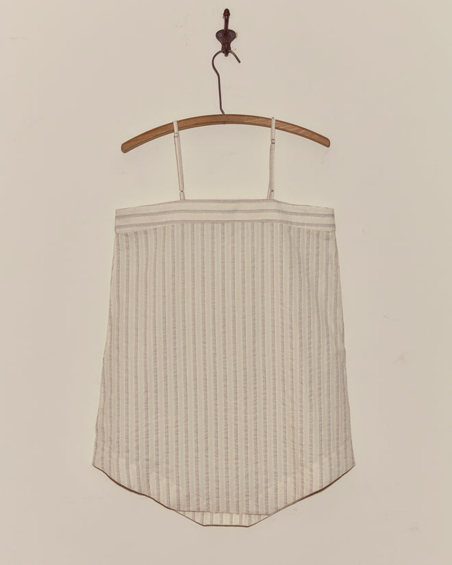 The Lavender Sail Teddy, a white striped camisole top made from antique shirting fabric, hangs on a wooden hanger against a plain white wall.