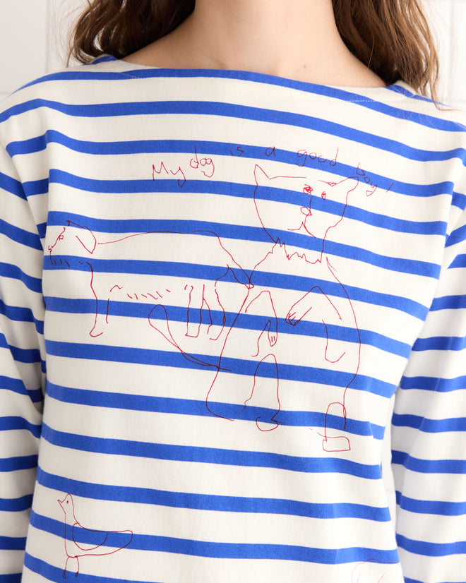A person in the Margate Dress, styled in blue and white stripes reminiscent of classic French Navy, sports hand-drawn red line art of dogs with the fun phrase