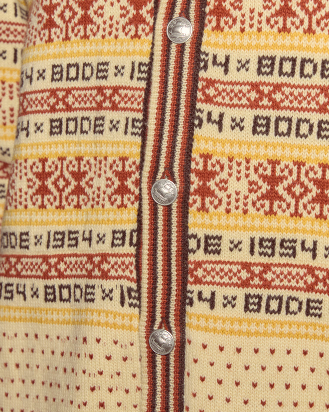 Close-up of the Marzipan Cardigan in virgin wool, featuring novelty silver ship buttons and rows of red, yellow, and brown Norwegian-inspired geometric patterns.