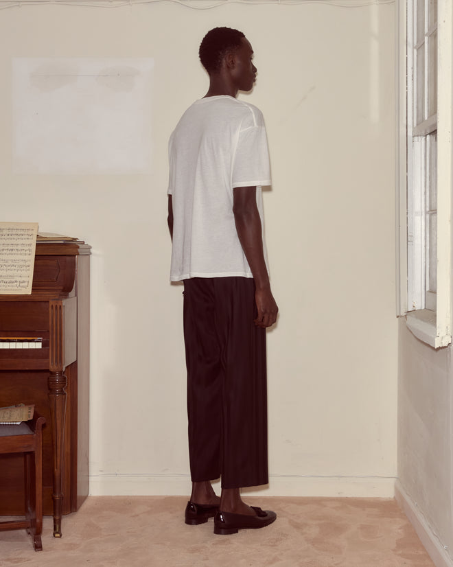Wearing the Theatre Tee and black pants, a person stands sideways in a room beside a piano and window, looking ready to audition for Broadway or dream of starring as Peter Pan at the Winter Garden Theatre.