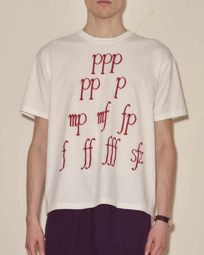 Individual wearing the Composer Tee, a white t-shirt with red musical dynamic symbols arranged in a pyramid design.