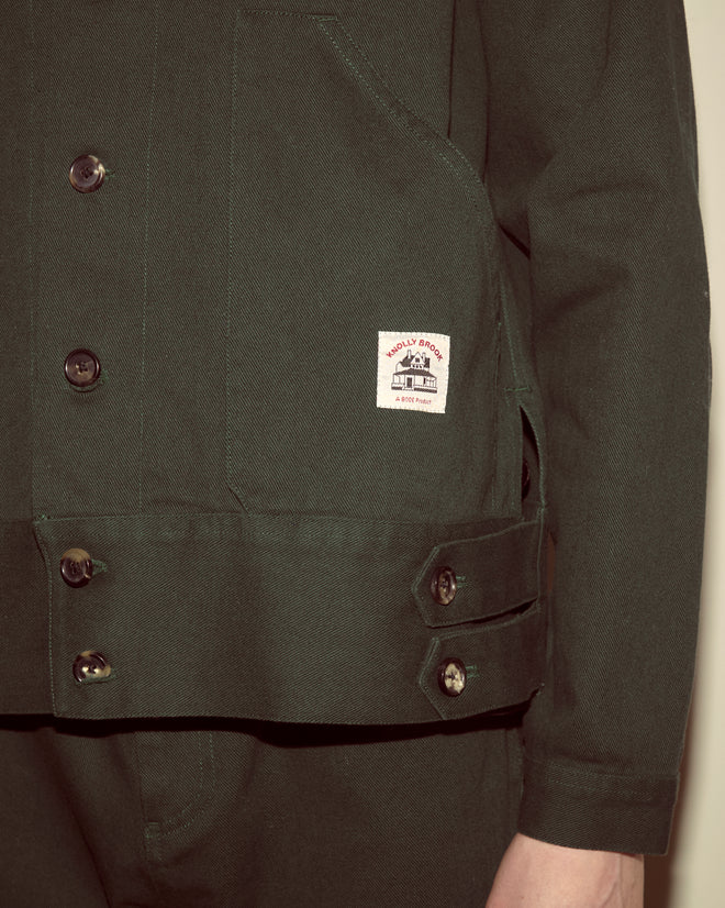 A person wears the Twill Knolly Brook Side Tab Jacket in dark green, featuring a visible label on the pocket.