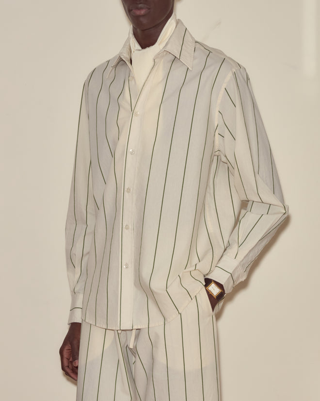 Person wearing the Celery Stripe Long Sleeve, a vintage-inspired shirt with 1930s-style stripes, paired with matching pants and a gold wristwatch.