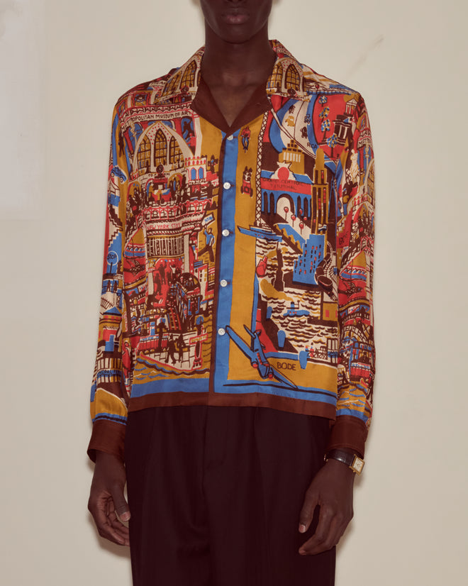 Man wearing the Manhattan Island Long Sleeve Shirt, featuring a colorful silk fabric with medieval and architectural Manhattan patterns, paired with black pants.