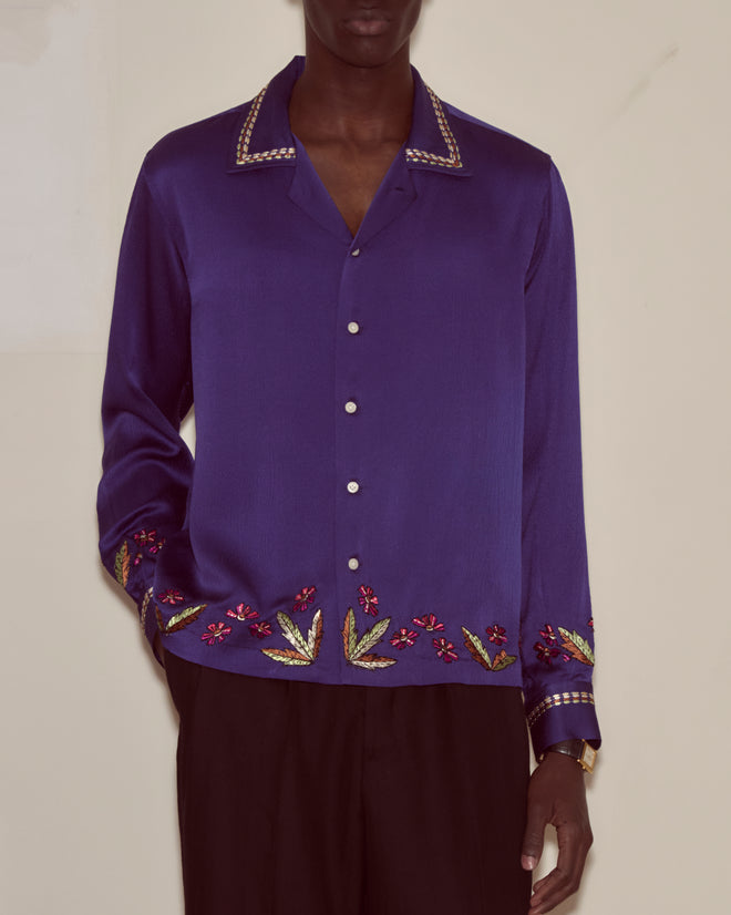 A person wearing the Dream Souvenir Long Sleeve in royal blue textured silk with Bode-inspired beaded floral patterns, paired with black pants.