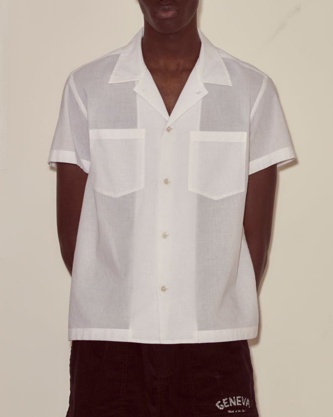 A person wearing the Voile Short Sleeve Shirt - White and dark shorts stands against a plain background.