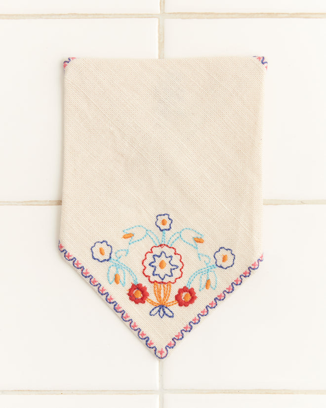 Garden Party Cocktail Napkins, featuring a colorful floral design, are embroidered linen napkins perfect for enhancing your table accessories, showcased on a tiled white background.