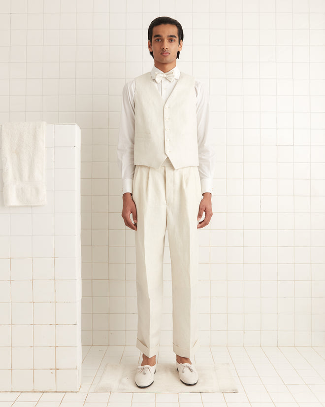 A person wearing a white shirt, Nelson Brookline Waistcoat, and trousers stands in a tiled room with a towel on the left, evoking a 1940s-1950s style.
