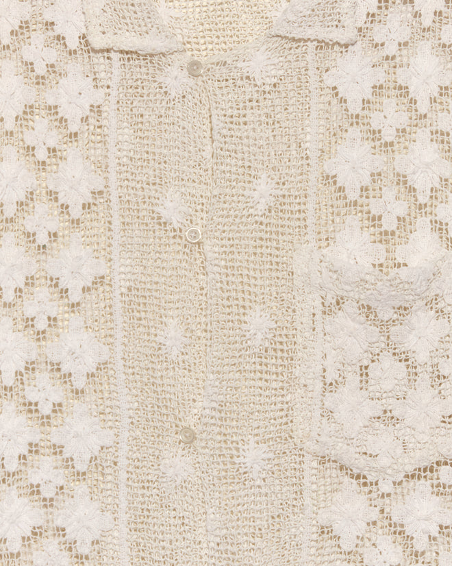 Close-up of the Netted Flower Shirt - S, a cream-colored crocheted top with floral patterns, buttons, and a small front pocket, reminiscent of 1930s lace shirts.