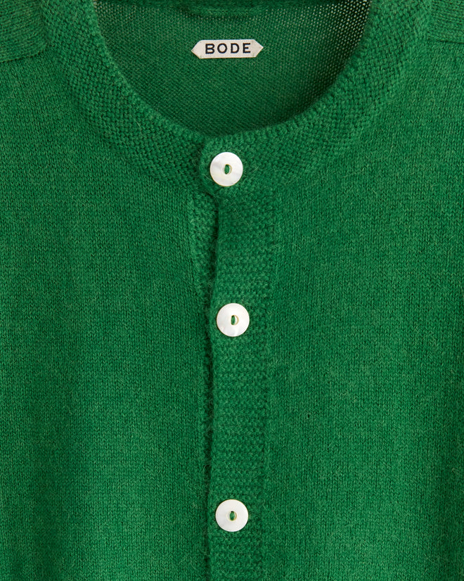The Orchard Cardigan in Kelly Green is a merino wool knit with antique pearl buttons and a “BODE” label at the collar.