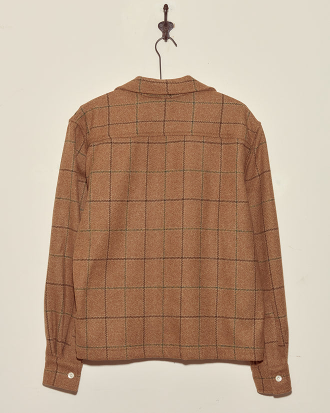 Pinscher Check Overshirt - M/L in brown plaid wool, long-sleeve deadstock style, shown hanging on a wall hook from the back against a light background.