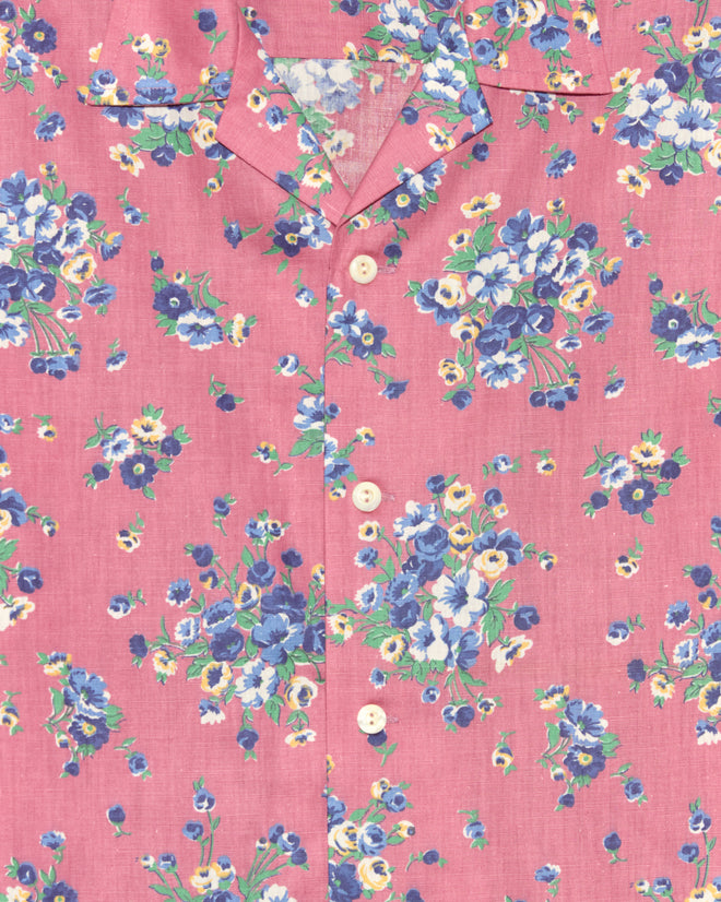 The Plum Shower Shirt features a pink base with blue, white, and yellow florals and classic white front buttons—an original piece that adds a unique touch to your wardrobe.