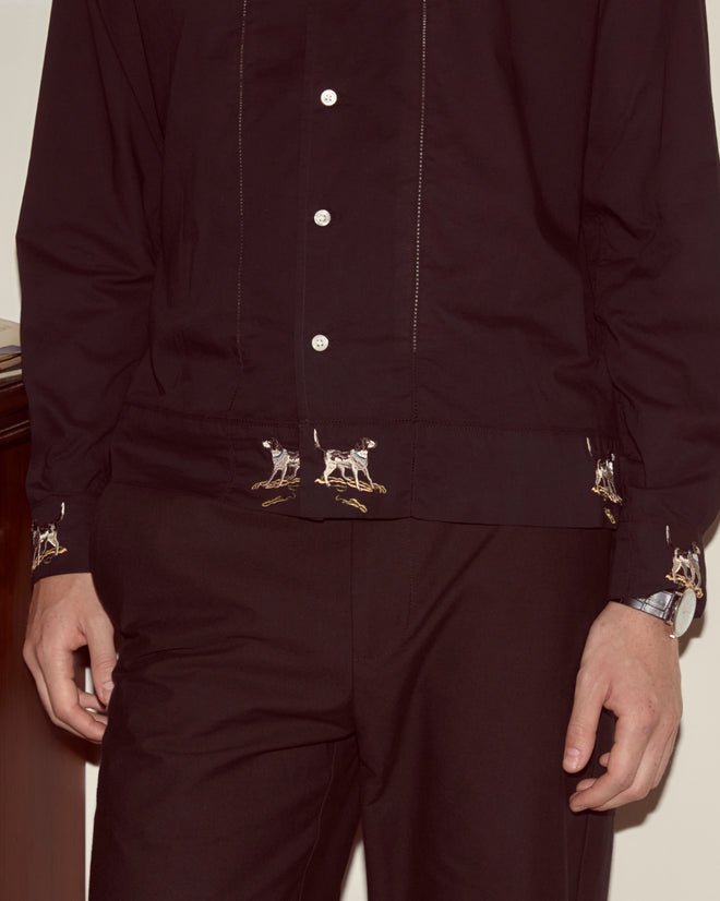 Person wearing the Pointer Long Sleeve Shirt, a black cotton top with ladderwork details and an embroidered dog motif near the cuffs, paired with matching dark trousers.