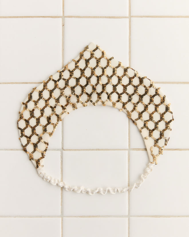 The Pinnacle Crown is a beaded, crown-like headpiece with a hexagonal pattern, reminiscent of a historical reproduction crown, displayed on a tiled surface.