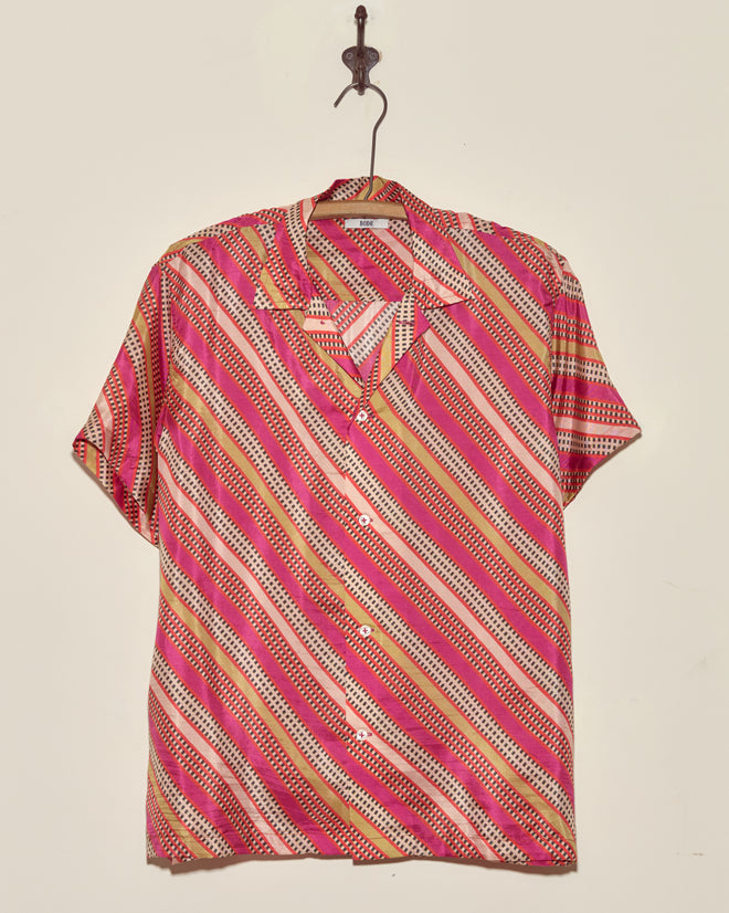 The Railhead Blooms Shirt - M/L is a unique short-sleeve shirt with red, pink, yellow, and white diagonal stripes, made in New York and displayed on a hook.