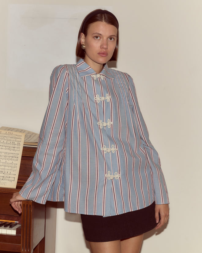 Woman in a Regatta Stripe Jonas Shirt and black skirt stands by a piano with sheet music, facing the camera.