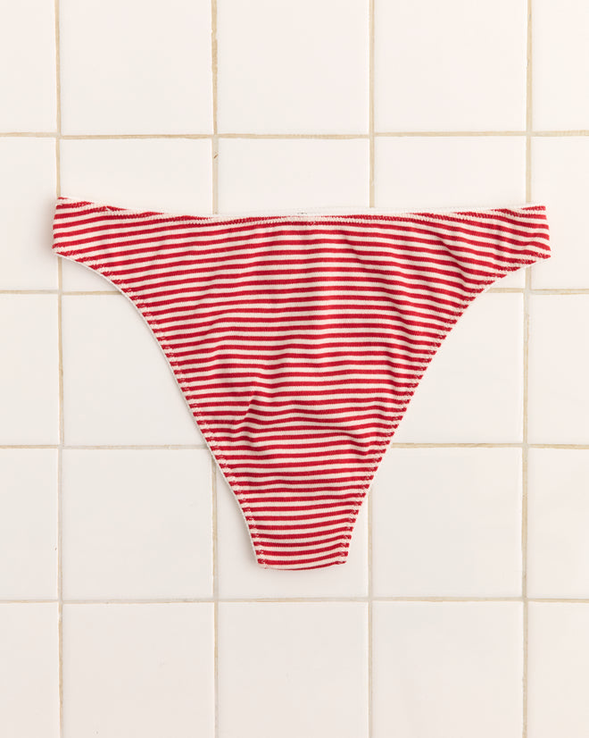 Sailboat Briefs featuring red and white stripes and an appliquéd sailboat patch hang against a white tiled wall.