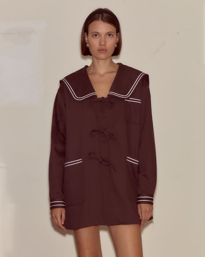 Model wears the Sailor Coat - Brown, a long, boxy fit coat with white trim and sailor collar inspired by 1960s nautical styles, against a plain background.