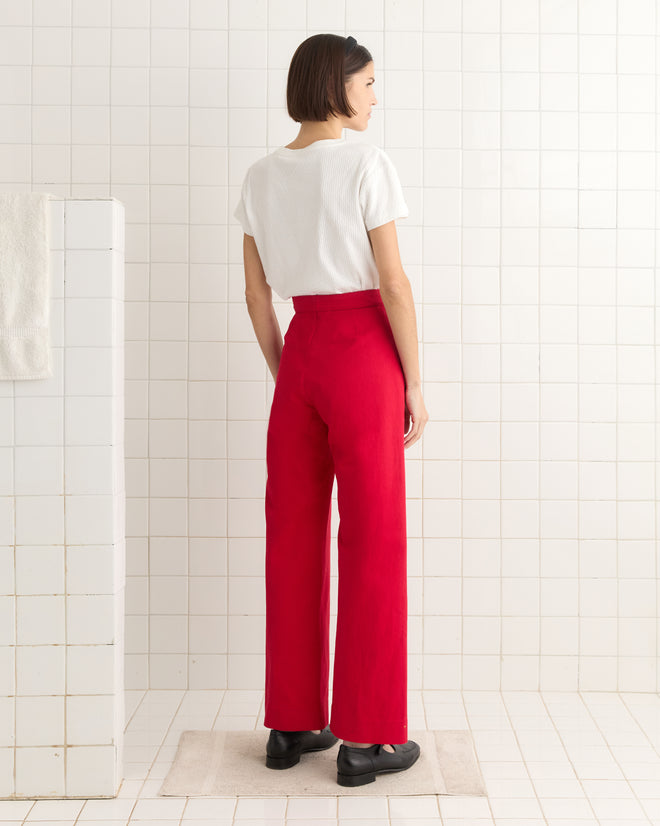 A person in a white shirt and Spring Twill Sailor Trousers stands on a mat in a tiled room, facing away.