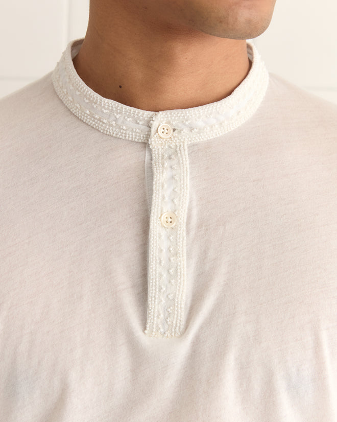 Close-up of someone wearing the Salt Marsh Polo, featuring an off-white shade, decorative collar, button placket, and tonal beadwork.