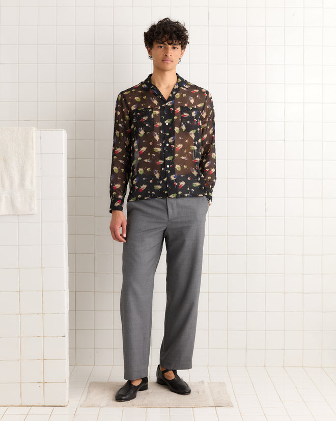 A person wearing the Sheer Midnight Daisy Shirt, gray trousers, and black loafers stands in a tiled room.