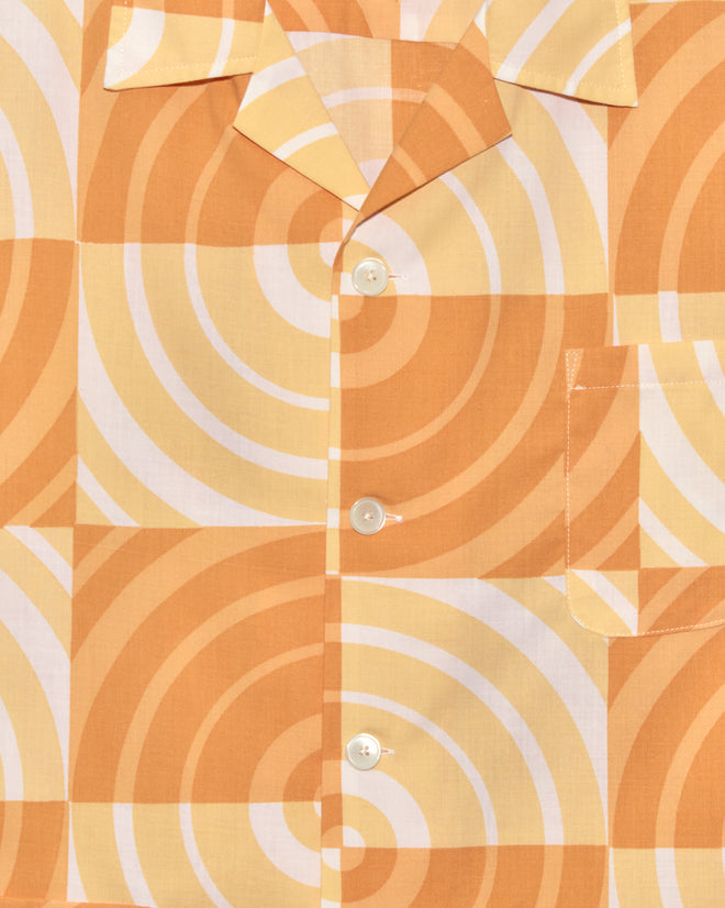 Close-up of the Sherbert Swirl Shirt, showcasing a unique orange and yellow geometric swirl design with classic white buttons.