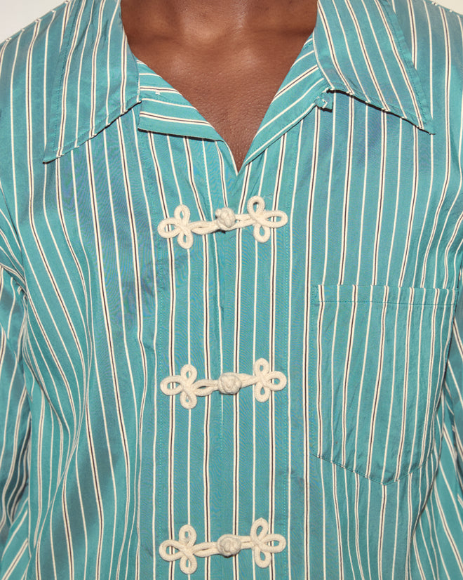 Person wearing a Shore Stripe Long Sleeve Shirt, designed with blue and white stripes, front pocket, and unique knotted frog closures.