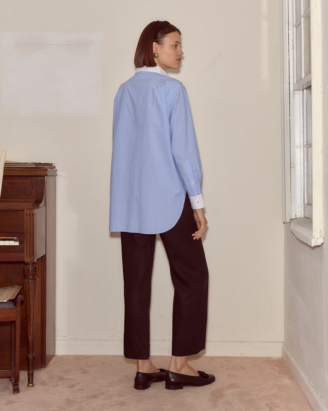 Woman wearing a vintage Signet Murray Shirt and black pants stands in a room near a window and an upright piano.