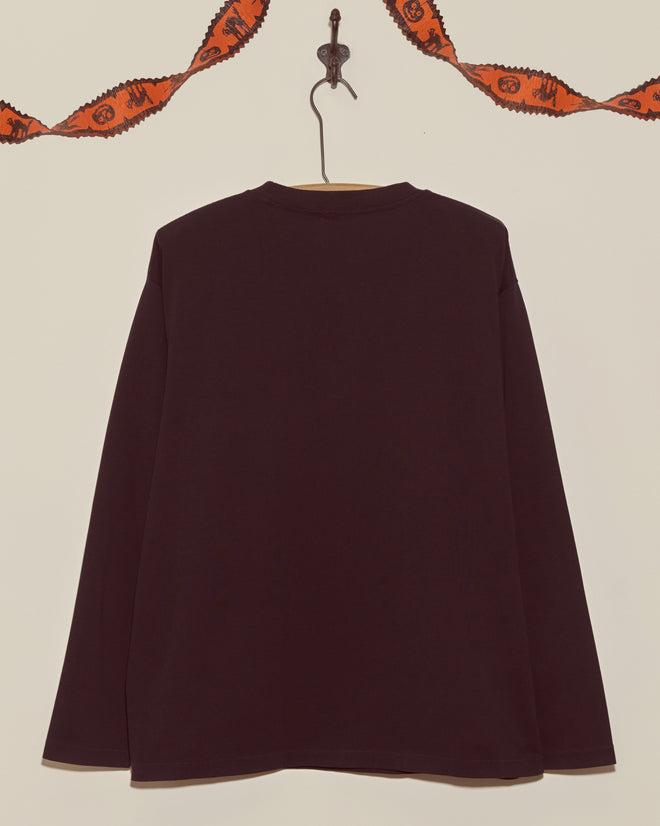 The Skeleton Long Sleeve Tee, a black shirt displayed on a hook beneath orange Halloween garland, brings vintage Halloween vibes—perfect for the season.